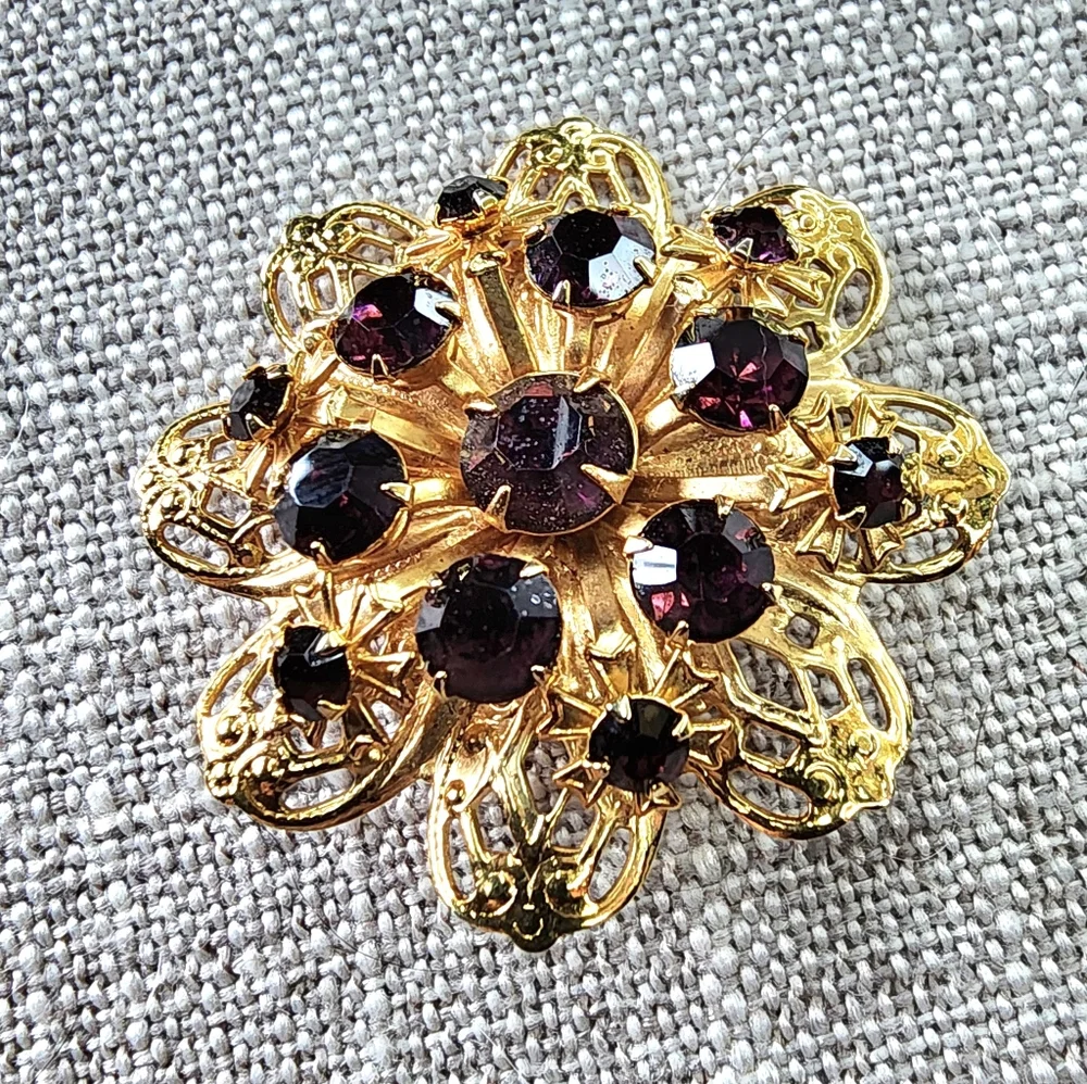 Vintage gold-toned round floral pin/brooch w/ deep violet rhinestones. 1960's